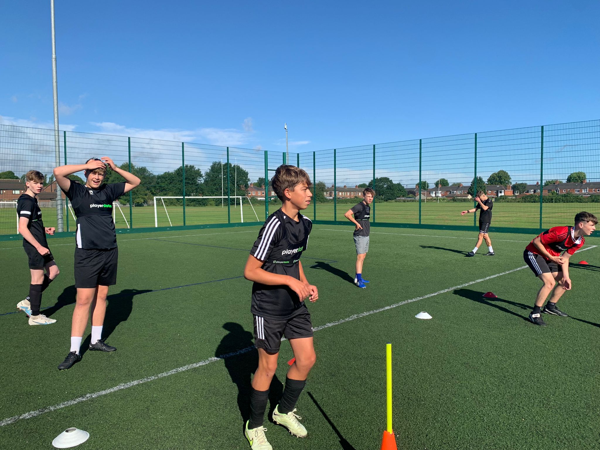 Football coach and athlete analyzing long-term physical development metrics on the pitch